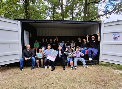 Der Container am Schwimmbad ist jetzt offiziell für alle geöffnet. Das Team der Kinder- und Jugendförderung (Jahn Scheel (r.), Jacqueline Garski (2.v.r. oben), Ralli Kaita (Mitte oben)), Bernd Langmann vom Kinder- und Jugendparlament (3.v.l. unten), Schwimmbadleiter Daniel Rau (l. unten), Bürgermeister Steffen Ball (Mitte unten) sowie Kinder und Jugendliche freuen sich über den neuen Begegnungsort.